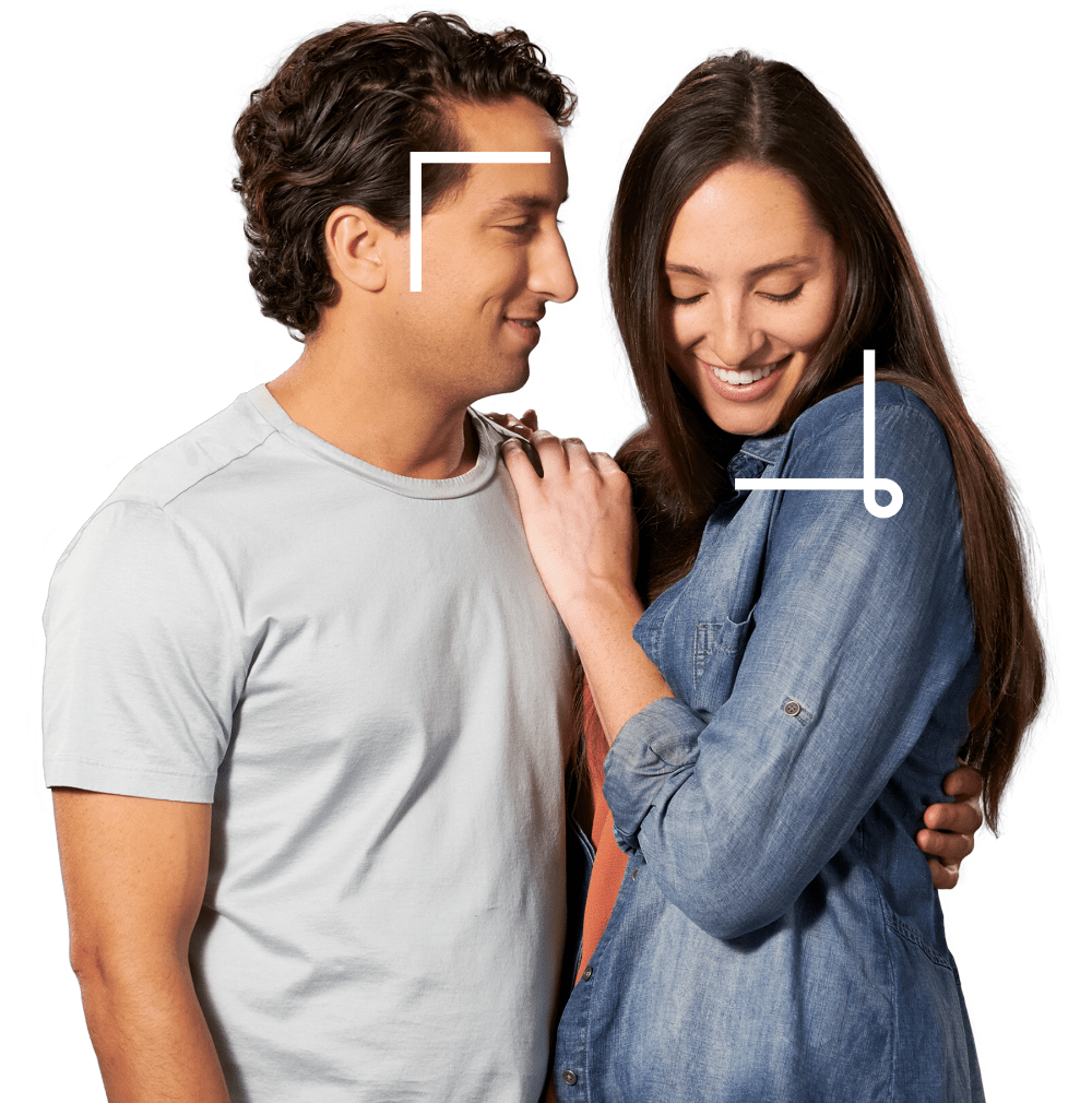 Young man smiling at his partner as she glances down with her hand on his shoulder